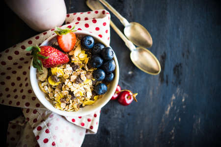 Healthy breakfast with oatmeals and organic berries - blueberry and strawberry on dark wooden table with copyspaceの写真素材