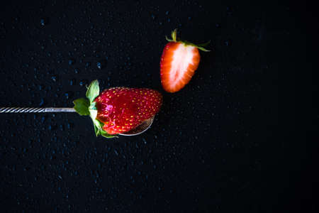 Ripe strawberry on vintage metal spoon on dark background with copyspaceの写真素材