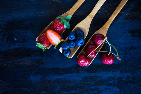 Summer fruits on spoons on wooden background with copyspaceの写真素材