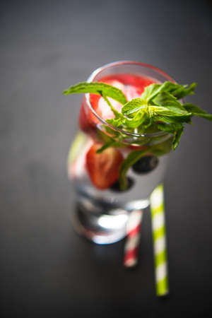 Detox organic drink with strawberries, blueberries and mint on dark wooden tableの写真素材