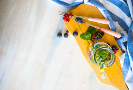 Detox summer drinks with fresh mint leaves and berries on white rustic wooden tableの写真素材