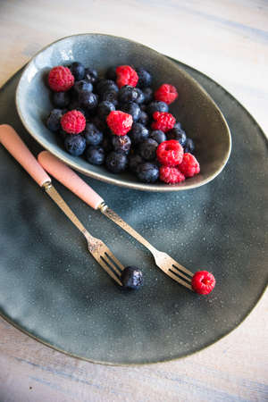 Fresh summer berries on white wooden rustic table with mint leaves