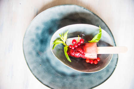 Summer fruit dessert - strawberry lollipops with mint and ice on rustic plate on concrete backgroundの写真素材