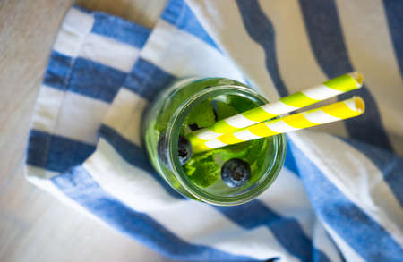 Detox summer drinks with fresh mint leaves and berries on white rustic wooden tableの写真素材