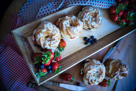 Dessert profitrole with vanila cream and ripe fresh berries like a strawberry, bilbery and rapsberry