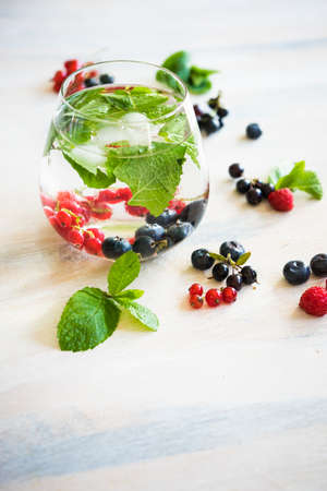 Detox summer drinks with fresh mint leaves and berries on white rustic wooden tableの写真素材