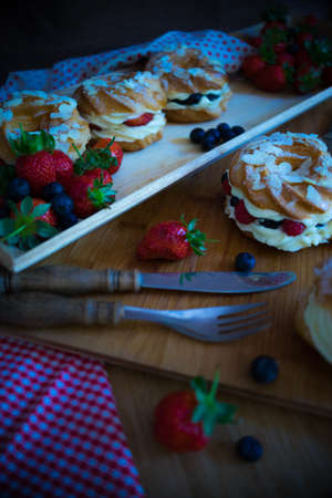 Dessert profitrole with vanila cream and ripe fresh berries like a strawberry, bilbery and rapsberry