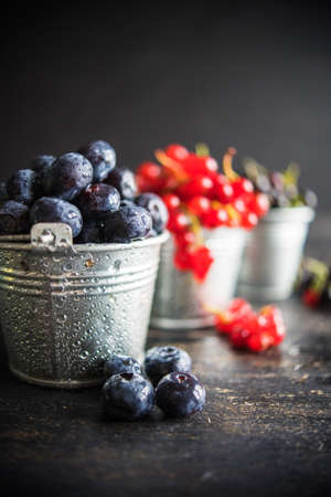 Ripe organic bilberries and currants on dark wooden table with copyspace as a organic food conceptの写真素材