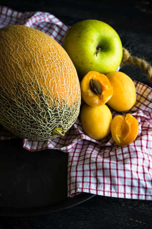 Ripe organic melon and apricots  on dark wooden table with copyspace as a organic food conceptの写真素材