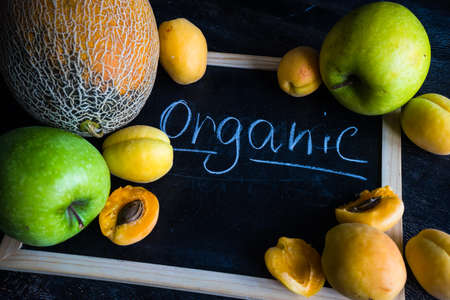 Ripe organic melon and apricots  on dark wooden table with copyspace as a organic food conceptの写真素材
