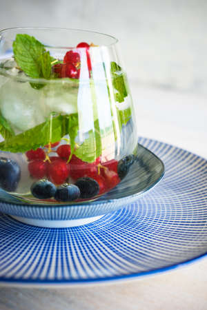 Detox summer drinks with fresh mint leaves and berries on white rustic wooden tableの写真素材