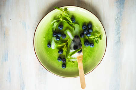 Summer fruit dessert - bilberry lollipops with mint and ice on rustic plate on concrete backgroundの写真素材