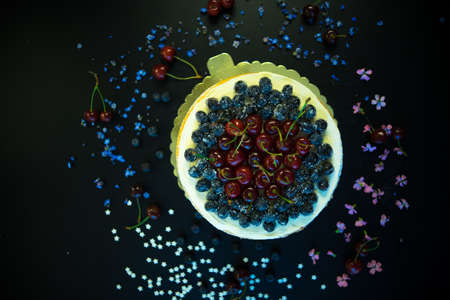 Festive cake decorated with fresh cherries and flowers on dark wooden tableの写真素材