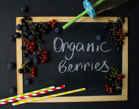 Ripe organic bilberries and currants on dark wooden table with copyspace as a organic food conceptの写真素材