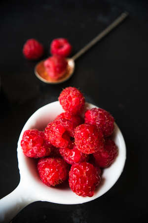 Ripe organic raspberries on dark wooden table with copyspace as a organic food conceptの写真素材
