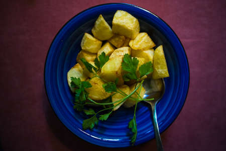 Fresh fried potatoes with parsley herb on blue plateの写真素材