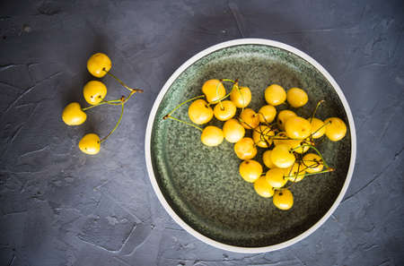 Organic food concept ripe yellow sweet cherries on rustic wooden table with copyspaceの写真素材
