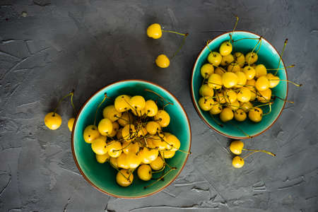 Organic food concept ripe yellow sweet cherries on rustic wooden table with copyspaceの写真素材