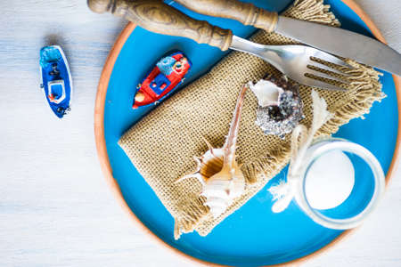 Summer vacation marine table setting with rustic plates and silverware on wooden background with copyspaceの写真素材