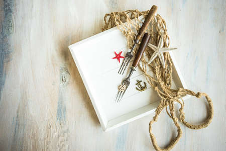 Summer vacation marine table setting with rustic plates and silverware on wooden background with copyspaceの写真素材