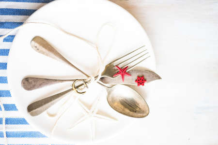 Summer vacation marine table setting with rustic plates and silverware on wooden background with copyspaceの写真素材