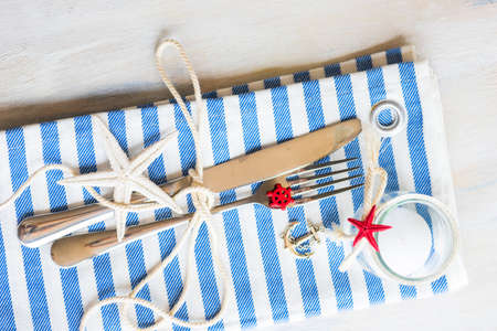 Summer vacation marine table setting with rustic plates and silverware on wooden background with copyspaceの写真素材