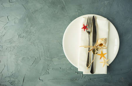 Summer vacation marine table setting with rustic plates and silverware on wooden background with copyspaceの写真素材