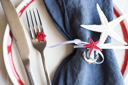 Summer vacation marine table setting with rustic plates and silverware on wooden background with copyspaceの写真素材