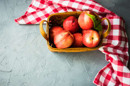 Ripe nectarine fruits in a busket on grey concrete table with copyspaceの写真素材