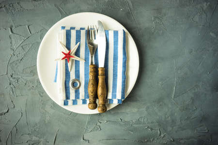 Summer vacation marine table setting with rustic plates and silverware on wooden background with copyspaceの写真素材