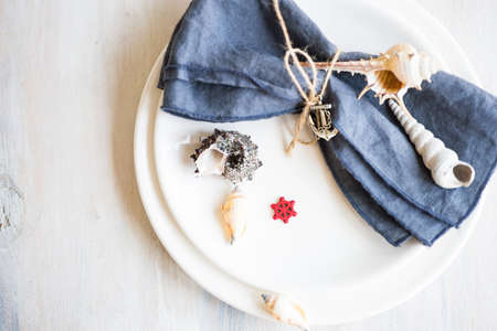 Summer vacation marine table setting with rustic plates and silverware on wooden background with copyspaceの写真素材