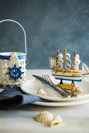 Summer vacation marine table setting with rustic plates and silverware on wooden background with copyspaceの写真素材
