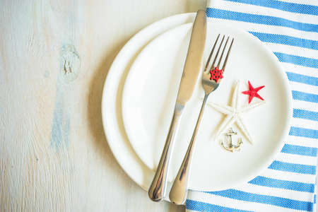 Summer vacation marine table setting with rustic plates and silverware on wooden background with copyspaceの写真素材