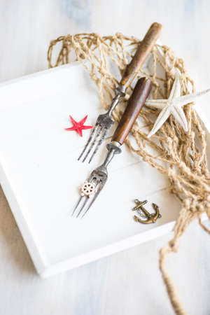 Summer vacation marine table setting with rustic plates and silverware on wooden background with copyspaceの写真素材
