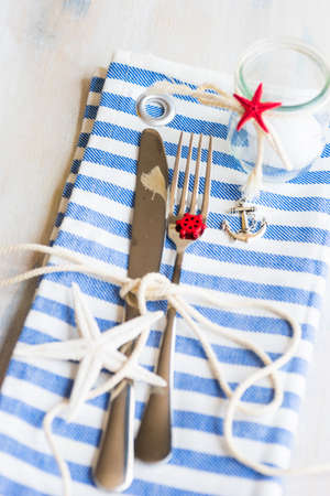 Summer vacation marine table setting with rustic plates and silverware on wooden background with copyspaceの写真素材