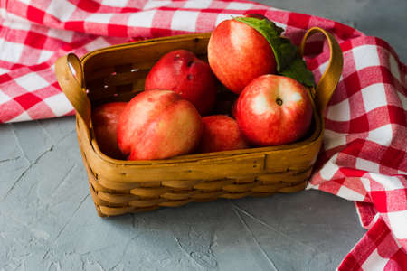 Ripe nectarine fruits in a busket on grey concrete table with copyspaceの写真素材