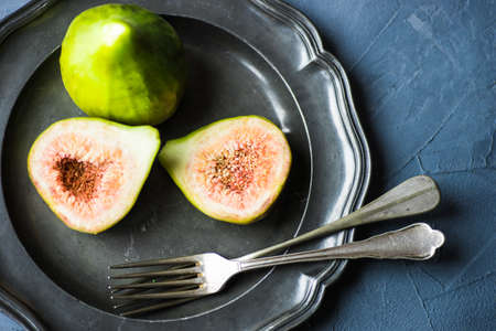 Organic fig tree fruits on the vintage plate on concrete background with copyspaceの写真素材