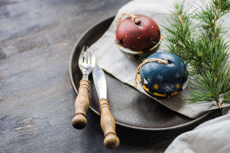 Table setting for festive Christmas dinner on dark wooden table with vintage plates and silverwareの写真素材