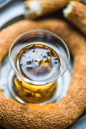 Glass of tea and traditional turkish snack - simit, on dark wooden tableの写真素材