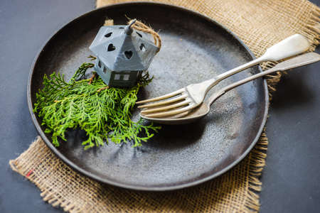 Table setting for festive Christmas dinner on dark wooden table with vintage plates and silverware