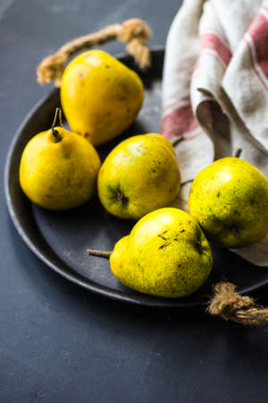 Organic pear fruits on the vintage plate on wooden background with copyspaceの写真素材