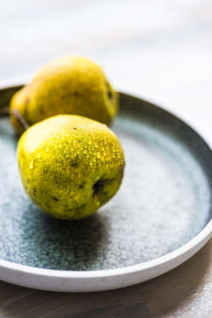 Organic pear fruits on the vintage plate on wooden background with copyspaceの写真素材