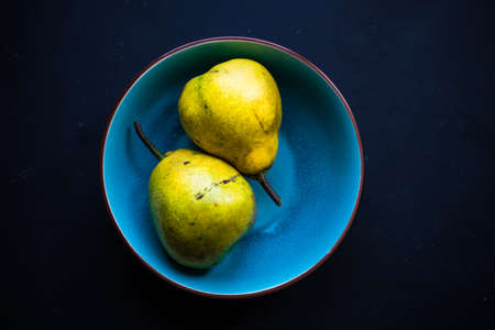 Organic pear fruits on the vintage plate on wooden background with copyspaceの写真素材
