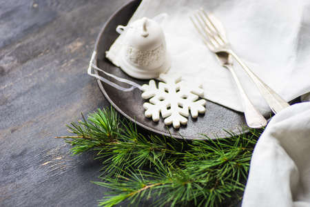 Table setting for festive Christmas dinner on dark wooden table with vintage plates and silverware