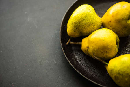 Organic pear fruits on the vintage plate on wooden background with copyspace