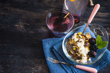 Oatmeal with chia and blackberries as a organic breakfast concept and detox drink of blackberries and lemon on dark rustic tableの写真素材