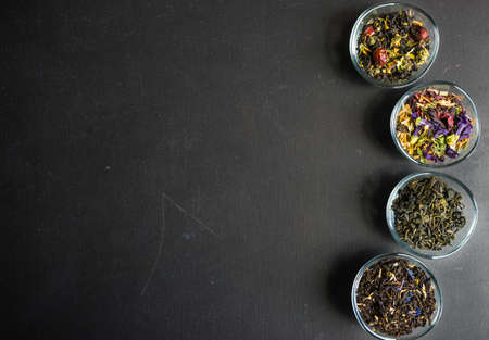 Different types of tea, green tea, peony and ginger tea, rose bud and wild flowers tea on dark wooden background with copyspaceの写真素材