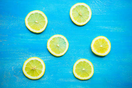 Summer fruit concept with slices of ripe yellow lemon on rustic wooden background with copyspaceの写真素材