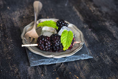 Fresh organic blackberries with mint and ice as a summer dessert concept on dark rustic table with copyspaceの写真素材