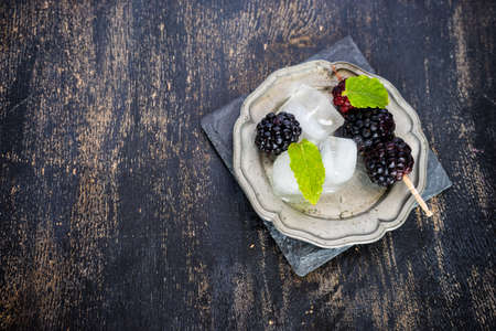 Fresh organic blackberries with mint and ice as a summer dessert concept on dark rustic table with copyspaceの写真素材